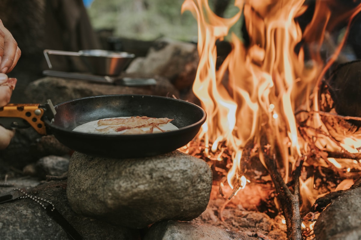 Cast iron skillet cooking over an open campfire