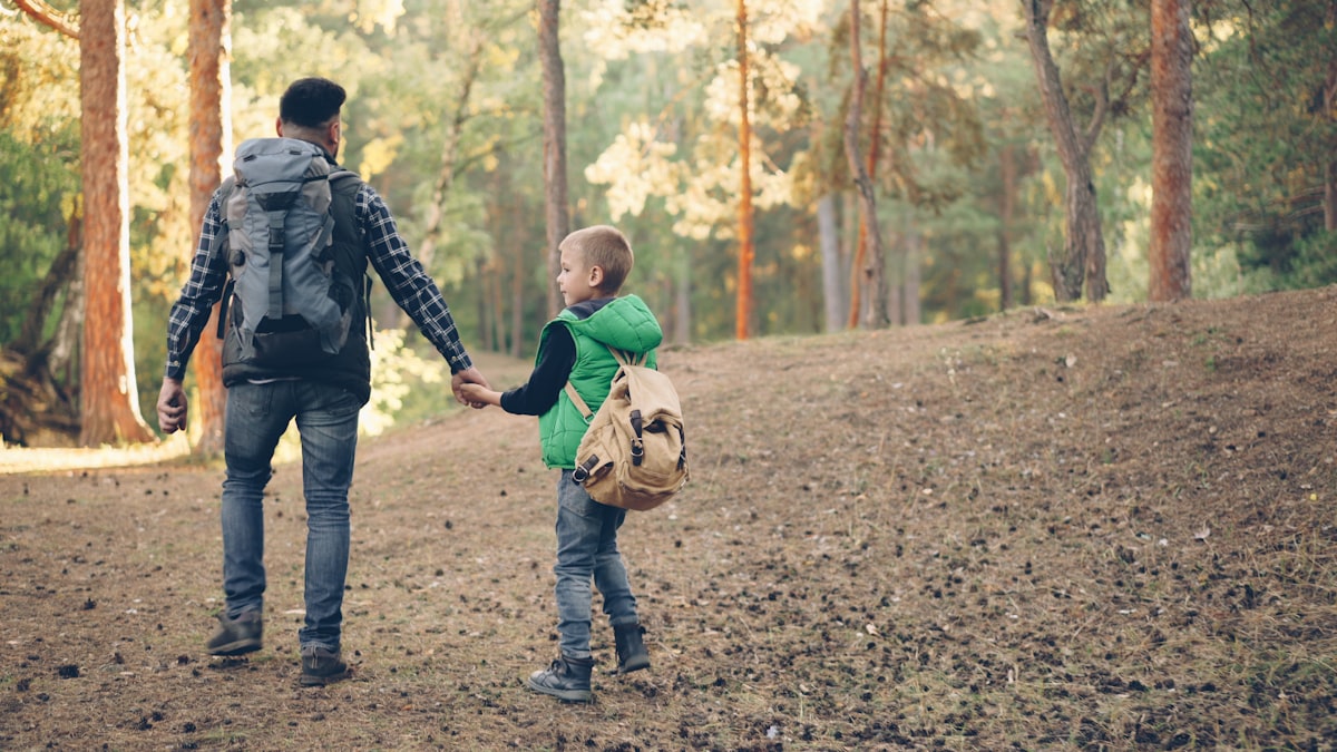A dad and kid hiking a woodland trail together